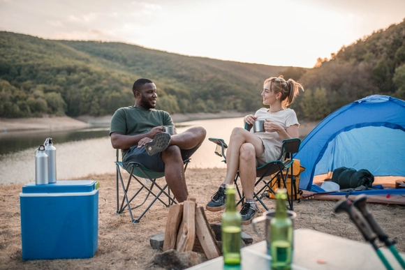 Zwei Personen unterhalten sich beim Campen an einem See.